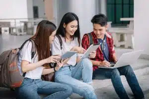 Group of students looking at their gadgets while sitting on the stairs.