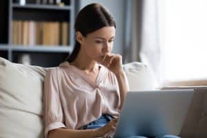 a female student thinking of something while using laptop