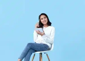 A student sitting on the chair, thinking intently while holding a notebook and pen.