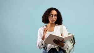 a curly girl thinking while holding her pencil and notebook