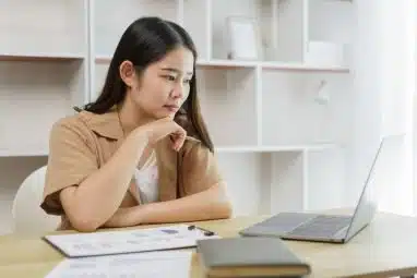 A female student looking at her laptop and thinking.