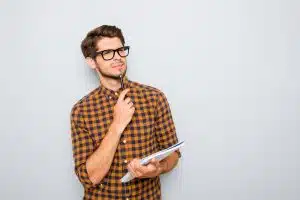 guy in plaid shirt contemplating with pen and notebook