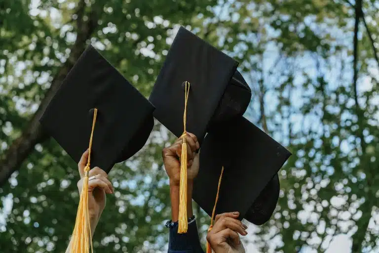 Three graduates preparing to throw their mortarboard caps in the air