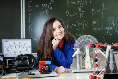 A student smiles while sitting at a science lab desk surrounded by equipment, symbolizing the academic excellence needed for Northwestern GPA requirements.