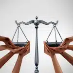 Multiple hands lift a balanced scale of justice, symbolizing themes related to political science programs for high school students.