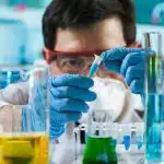 Chemist/Engineer holding a test tube inside a lab as he explores biomedical engineering summer programs for high school students