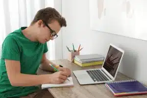 Teenager boy writing an essay at desk indoors