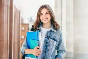 Young girl student smiling against university.