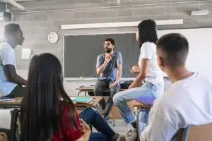 students listening and talking to male teacher