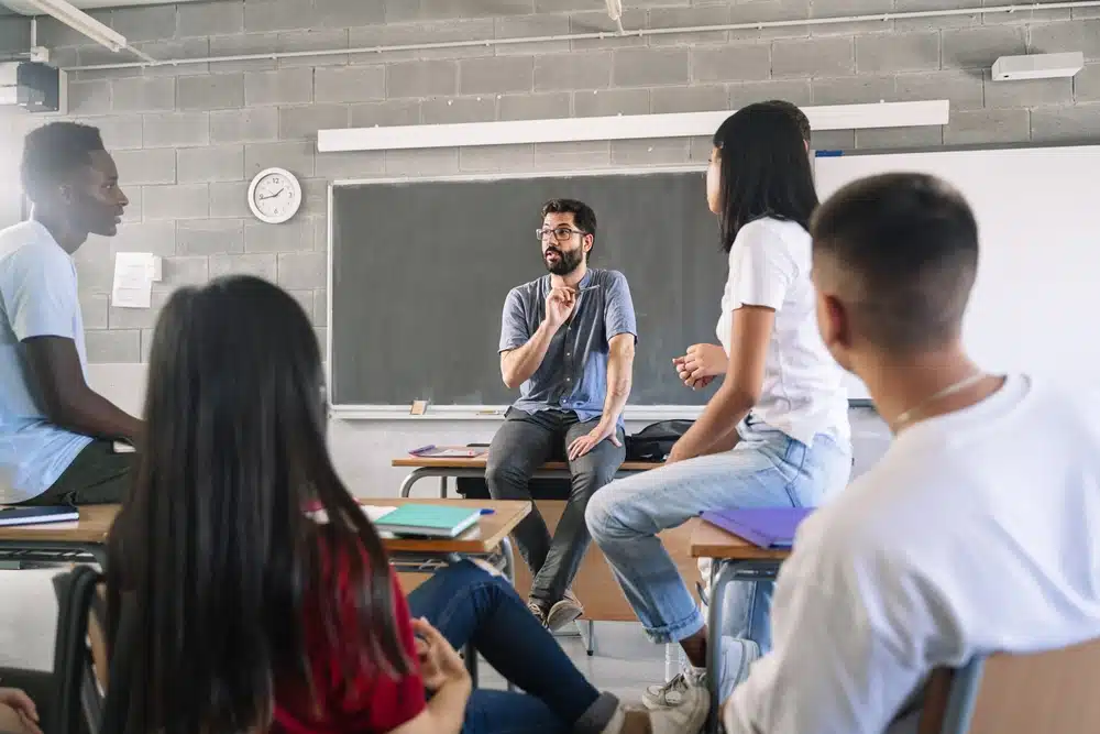 students listening and talking to male teacher