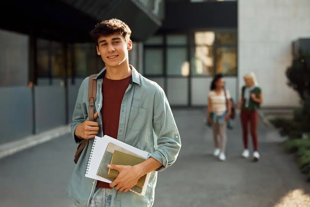 student in front of university building looking at camera