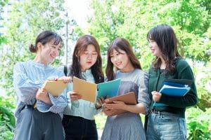 four Asian female college students looking at their notes