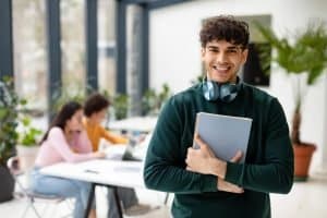 college student holding books and smiling at camera