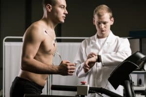 Man running on treadmill during medical test and medic in white uniform