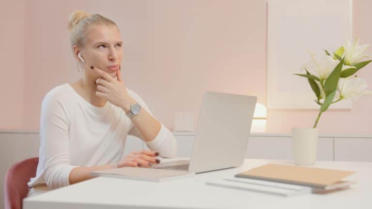 A young woman sits at a desk, thinking about the difference between Wellesley vs Barnard.