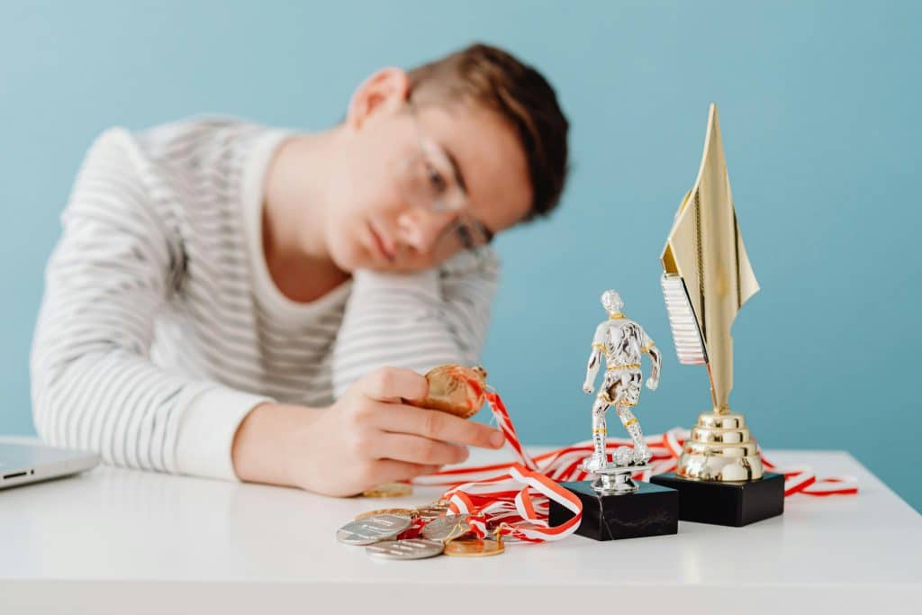 A male student examining medals and trophies on his desk