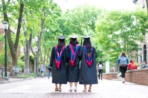 Image of three dark-haired women in graduation gowns.