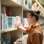 A young man in the library looking for psychology research topics for his thesis.