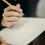 Student writing in a notebook while building skills for future writing opportunities