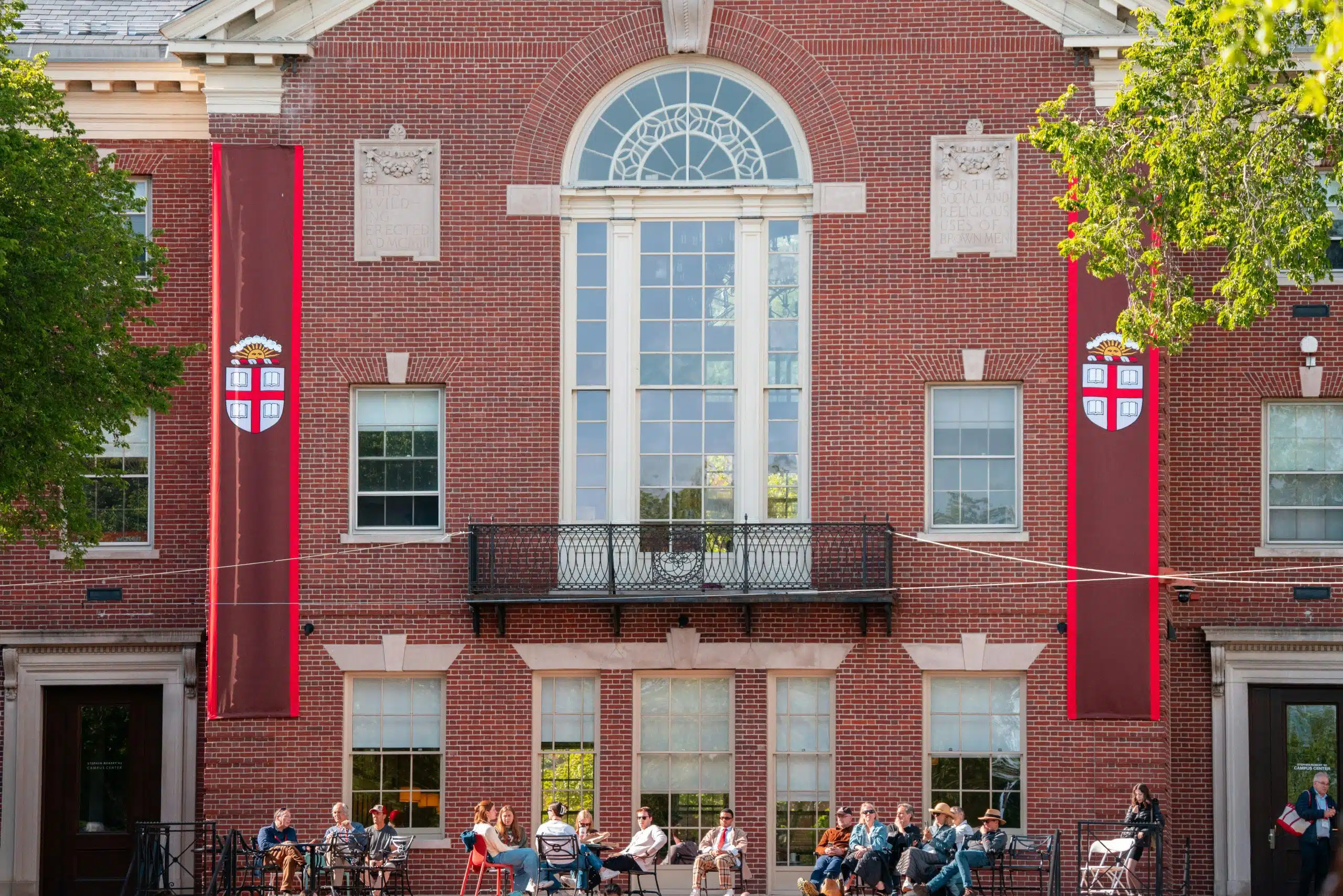 Students relaxing outside a historic campus building at Brown University, highlighting what Brown University is known for: Ivy League academics, open curriculum, and collaborative student life.