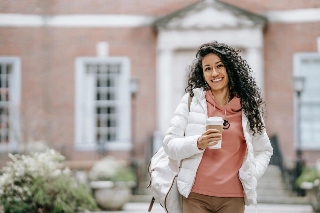 Student walking on campus with a coffee cup, representing preparation for the Wesleyan University application deadline.