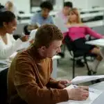 Student in brown sweatshirt sitting down studying SAT Vocabulary words