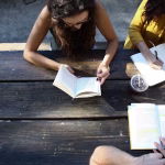students writing on a table outside