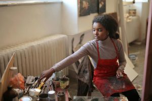 An art student holding paint brushes in an art studio