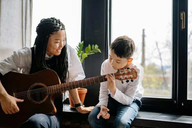 A high school student teaching a younger student to play music