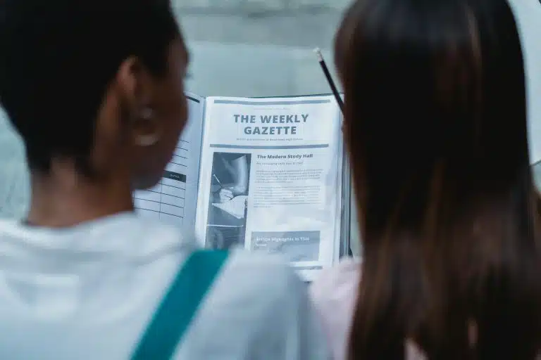 Two students examining the rough outline of a newspaper