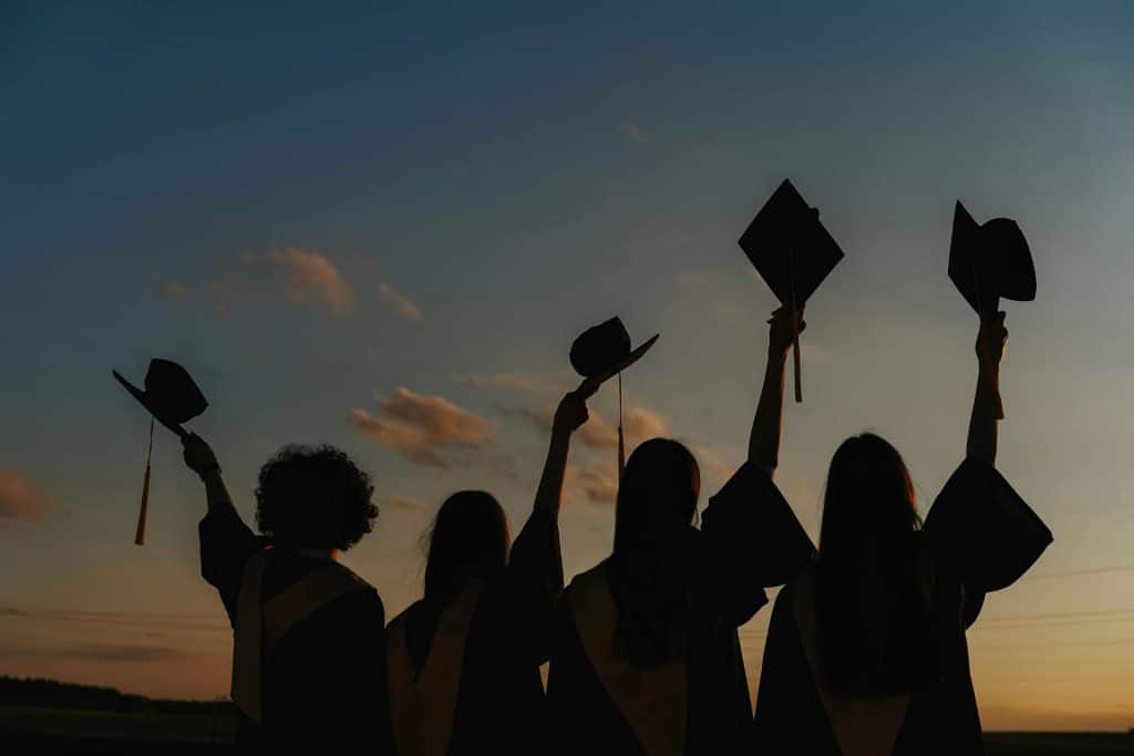 Silhouette of Brown University notable alumni raising their graduation hats