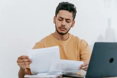 Man in orange shirt looking a sheet of paper