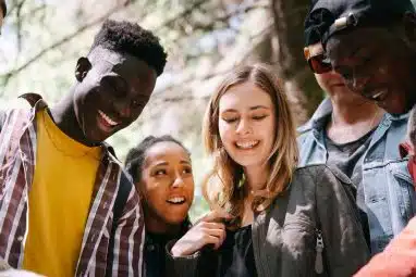 A group of young people smiling and engaging outdoors, embodying camaraderie and the Yale motto