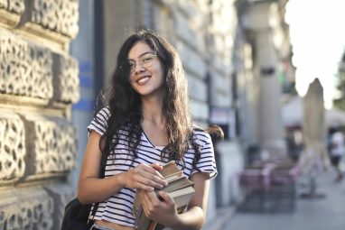 Smiling student holding books outdoors, representing Duke pre-college programs