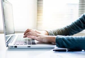 A person typing on a laptop searching for "college help near me"