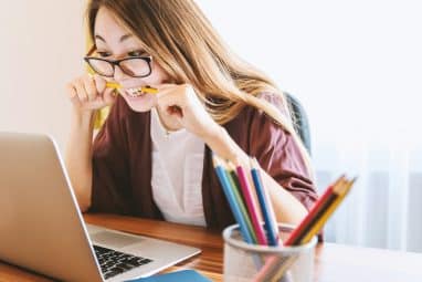 A student prepares for the Math Kangaroo competition while studying on a laptop and biting a pencil.