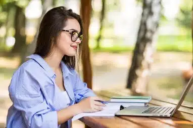 A student studies outdoors on her laptop while preparing for the National Technology Honor Society.