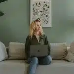 A person sitting on a sofa with a laptop, working on their materials before the Georgia Tech application deadline.