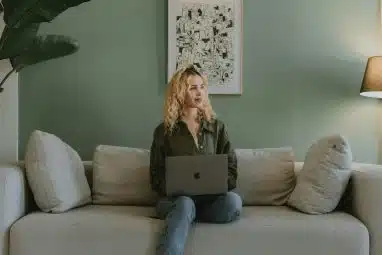 A person sitting on a sofa with a laptop, working on their materials before the Georgia Tech application deadline.