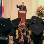Graduates raising their hands during a commencement ceremony, symbolizing academic achievement and leadership tied to institutions often led by the highest paid university presidents.