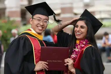 A male and female student who beat the USC yield rate, holding their diploma from the University of Southern California