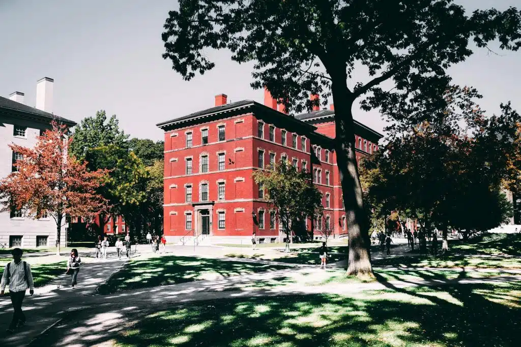 Red brick building in a university campus where students walk anticipating of when do college admission decisions come out.