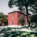 Red brick building in a university campus where students walk anticipating of when do college admission decisions come out.