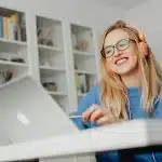 woman in blue sweater smiling looking at her computer for