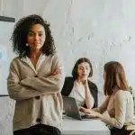 Student in beige smiling with colleagues preparing for the aspirations in computing award