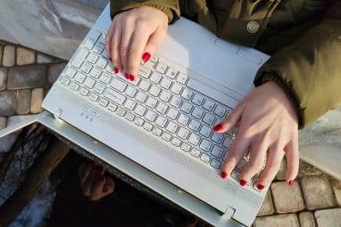 A person types on a laptop outdoors while researching Williams College SAT requirements.