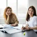 Two students studying together at a table with open books, representing preparation for Emory University SAT requirements.