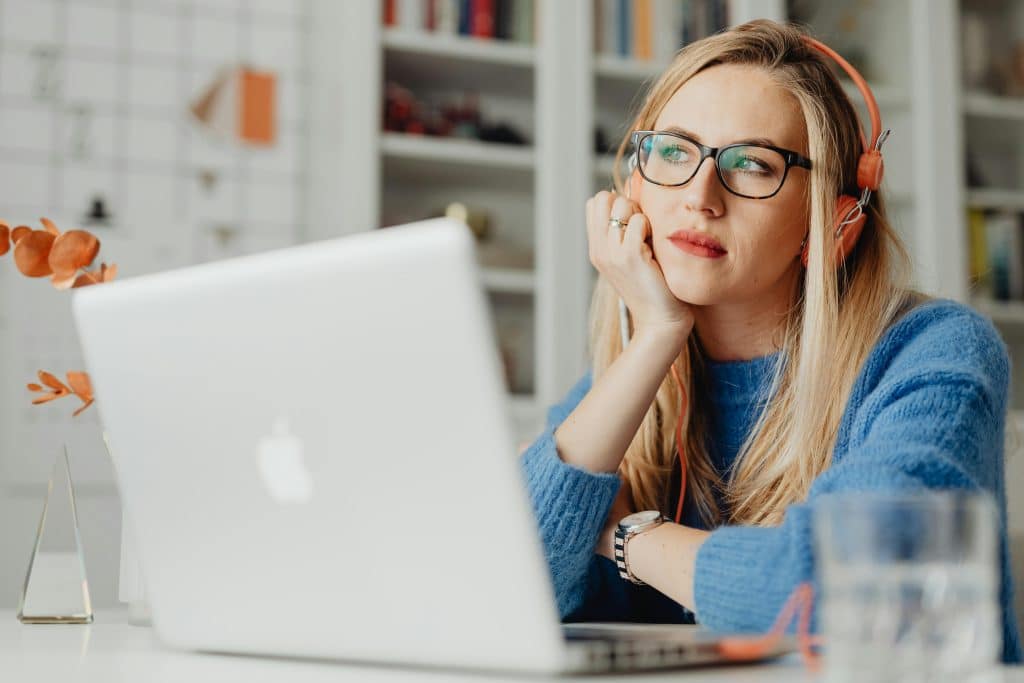 A student wearing headphones looks thoughtful while studying on her laptop, wondering how hard is the SAT.