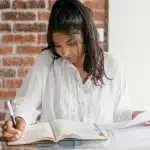 A high school student studying at a desk with notebooks and papers, representing Northeastern University GPA requirements.