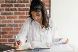 A high school student studying at a desk with notebooks and papers, representing Northeastern University GPA requirements.